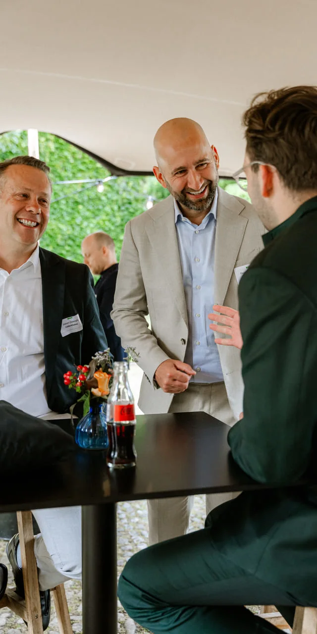 Twee gasten lachen met Tijl Kerckhove aan een statafel